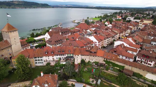 Idyllic Murten Switzerland. Aerial 4K. Medieval castle and red roofs of old town on scenic lake Morat. Canton Fribourg historic landmark. Swiss authentic villages