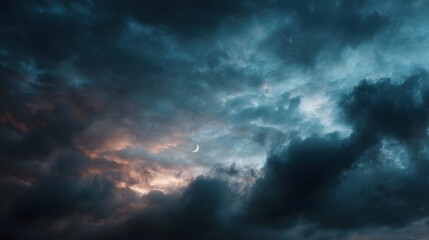Obraz premium A thin crescent moon peeks through dramatic stormy twilight clouds illuminated by an ethereal glow