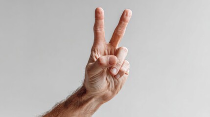 A human hand displaying the peace sign or victory gesture against a plain light gray background