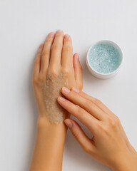 Close-up of woman exfoliating hand skin with blue crystal scrub. Beauty and skincare routine concept with natural light, soft background, moisturizing and spa treatment at home.