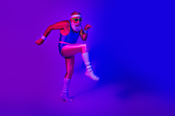 Energetic senior man in retro fitness outfit jumping under neon purple and blue lights for a dynamic sport lifestyle stock photo