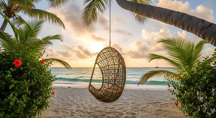 Wicker swing hanging from a palm tree on a tropical beach at sunset