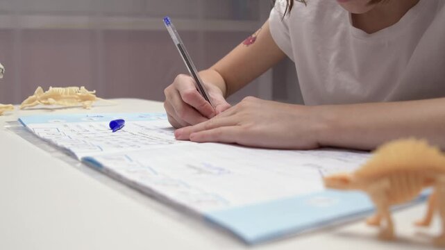Child doing homework at white desk in bright room, focused on writing in exercise book, atmosphere of learning and creativity.