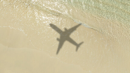 Aerial view of shadow passenger plane silhouette and sandy beach blue sea with waves at sea beach summer vacation sea travel concept	