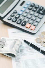 Concept of tax season and financial accounting. Stack of US dollar bills clipped on income tax...