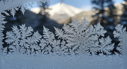 Intricate frost patterns on glass with snowy mountain background