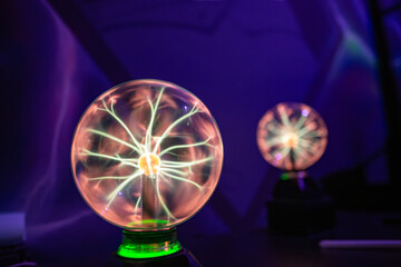 Two plasma ball lamps operating in the dark. Each globe shows electrical filaments, demonstrating the excitation of inert gases by a high-voltage, high-frequency electrode at the center.