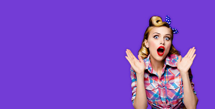 Portrait image - surprised cute woman with expressive wide open eyes, mouth, isolate purple background. Blond girl wear pinup retro vintage shirt raises hands, astonishment emotion. Free ad text space