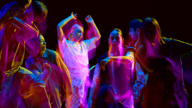 Street dancers moving in bright motion blur lights. Concept of creative performance, fashion promotion, and modern youth lifestyle advertising for social culture visuals.