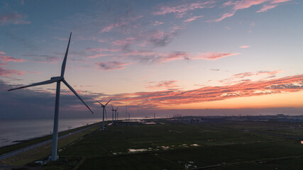 Obraz premium Aerial Sunset View of Coastal Windmills Against Flaming Sky