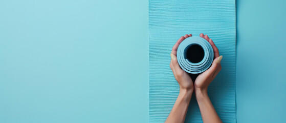 Hands holding rolled yoga mat on blue background, perfect for fitness or wellness themes