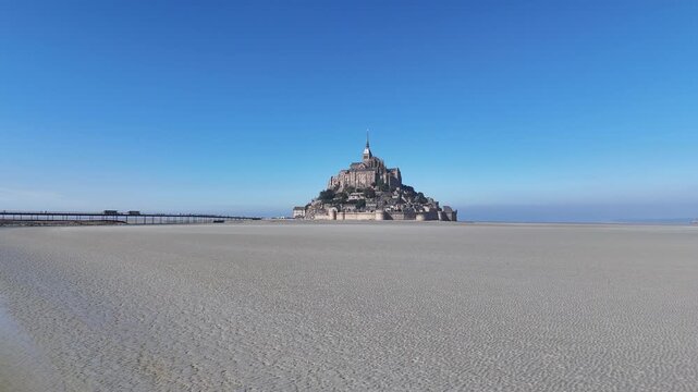 Aerial view of Mont Saint-Michel, a historic tidal island commune in Normandy, standing proudly against the clear blue sky, Mont Saint-Michel, Normandy, France.