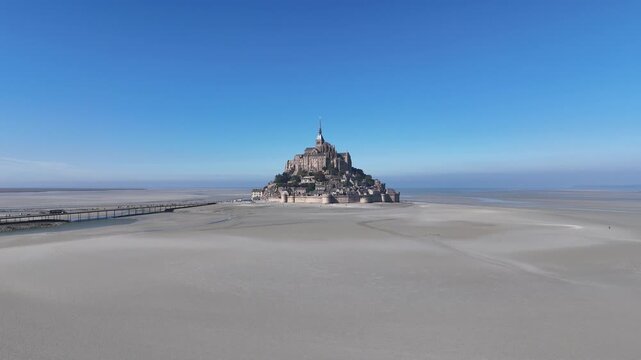 Aerial view of Mont Saint-Michel abbey and its causeway amidst the vast tidal plains, showcasing its majestic architecture, Mont Saint-Michel, Normandy, France.