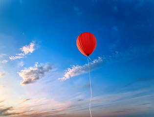 Obraz premium A red balloon floats against a blue cloudy sky