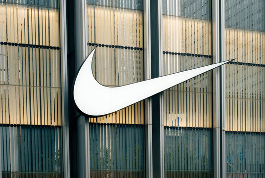 Shenzhen, China - November 4, 2025: A sign and the NIKE logo on the facade of a glass building. The exterior of a clothing store on a city street.