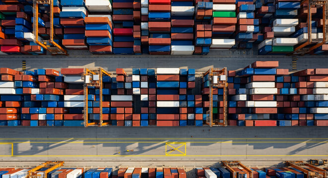 Aerial top down view of colorful shipping containers and gantry cranes in a commercial port terminal. Banner template of global logistics, export, import and supply chain concept.