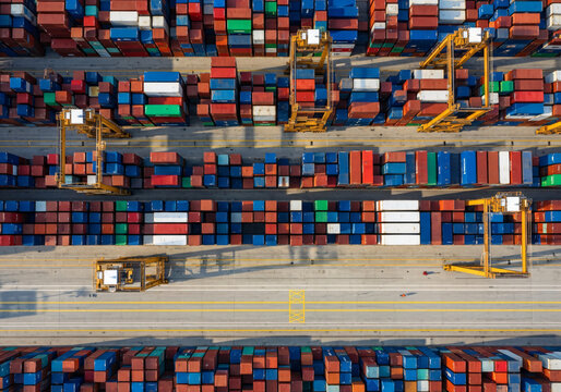 Aerial top down view of colorful shipping containers and gantry cranes in a commercial port terminal. Banner template of global logistics, export, import and supply chain concept.