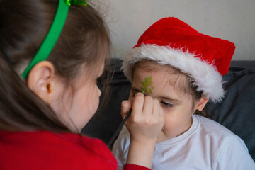 The older sister gives her younger sisters Christmas face painting.