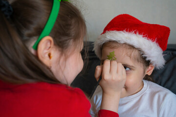 The older sister gives her younger sisters Christmas face painting.