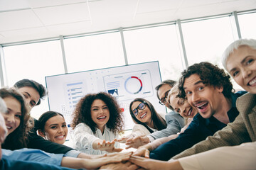 Fototapeta premium Diverse Team Smiling and Collaborating During a Dynamic Office Meeting With Presentation Display and Mutual Support