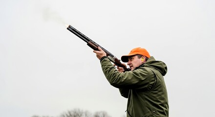 Naklejka premium Hunter aiming shotgun while shooting in overcast outdoor setting 