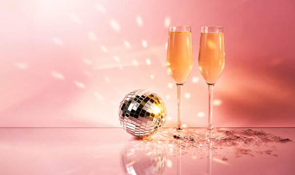 Celebration, festive, party time concept. Champagne glasses, disco ball on shining pink background. Valentines day, New year's eve, Birthday invitation.