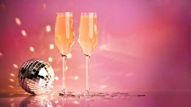 Celebration, festive, party time concept. Champagne glasses, disco ball on shining pink background. Valentines day, New year's eve, Birthday invitation.