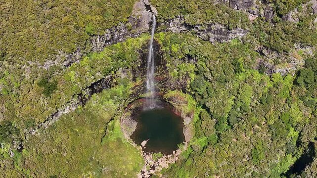Drone view of person swimming in refreshing Risco waterfall pool, Madeira