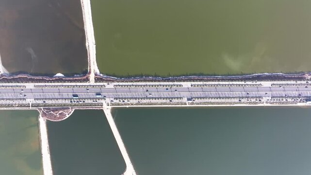 Aerial view of colorful salt ponds divided by roads, creating a geometric pattern of contrasting hues and textures, Yuncheng, China.