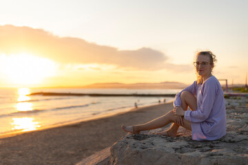 Young woman enjoying tranquil golden hour on beach at sunset
