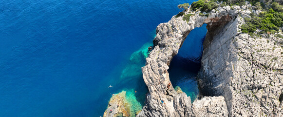 Aerial drone ultra wide panoramic photo of tropical exotic bay with crystal clear turquoise sea and sea caves forming a blue lagoon visited by small yachts and boats