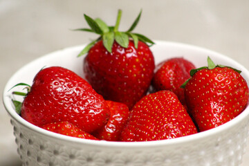 Juicy red strawberries in a white textured bowl, captured in close-up detail, symbolizing freshness, health, and natural sweetness.