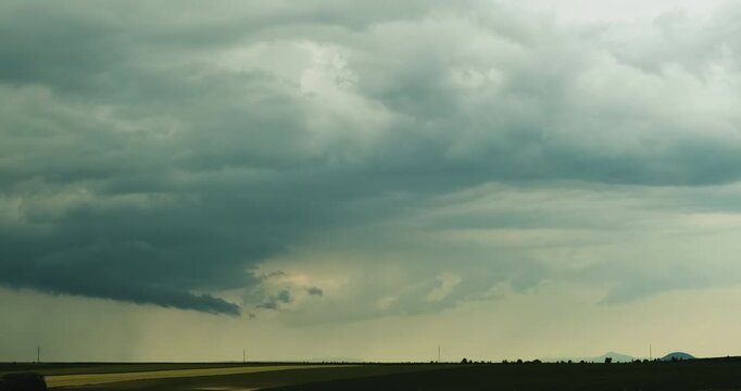 Rain Cloud Approaches Over Green and Yellow Fields Dropping Curtains of Rain While Expanding Cloud Cover Recasts the Landscape in a New Moody Tone in Cinematic 4K Time Lapse