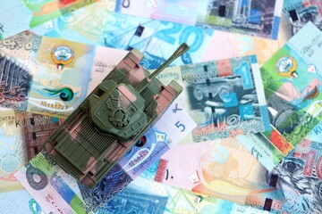 Kuwaiti dinar currency money bills and toy tank close up. The concept of army funds and weapons...