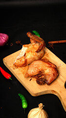 Roasted Chicken Pieces on Wooden Cutting Board with Spices and Vegetables
