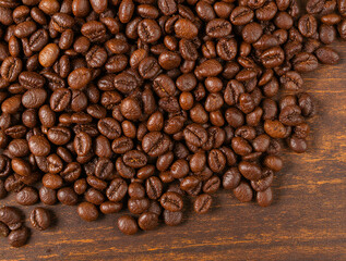Naklejka premium Close up of roasted coffee beans on a wooden surface