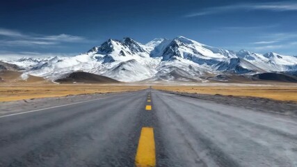 A long straight asphalt road with a yellow center line leads through a vast arid plain towards a majestic snow-covered mountain range under a clear blue sky - Powered by Adobe