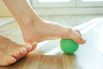 Person applying pressure with sole on textured green therapy ball during workout. Symbolizes functional fitness tool, neuromuscular activation, holistic health approach, and tension release method.