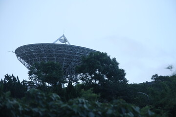 Fototapeta premium Taipei, Taiwan, - June 29th 2025 - A large, weathered satellite dish antenna at Yangmingshan Earth Station tilted towards the twilight sky.