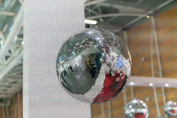 Mirror ball suspended in a nightclub with light shows, a vibrant nighttime atmosphere of music, dance, and movement, an iconic symbol of fun in clubs, parties, and soirees. New Year's Eve, web news.
