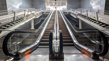 Escalators lead to a bright in modern metro train station in the heart of the city. Urban progress...