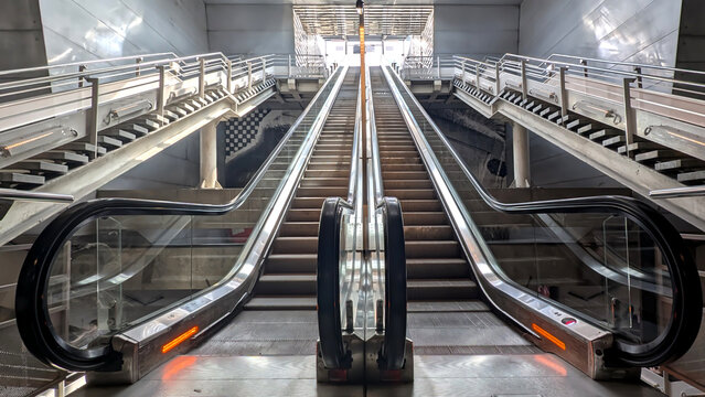 Escalators lead to a bright in modern metro train station in the heart of the city. Urban progress and movement concept - Powered by Adobe
