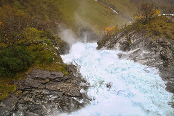 Dynamic waterfall in rocky autumn landscape with bubbling water.