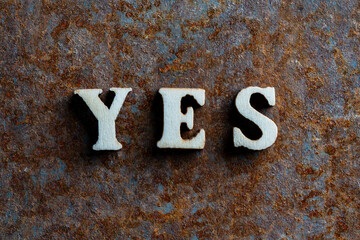 Wooden letters with the word yes on an old rusty surface, closeup, top view. Business, motivation and education concept