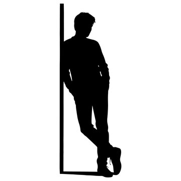 Silhouette of a young man leaning against a wall with crossed legs and hands in pockets