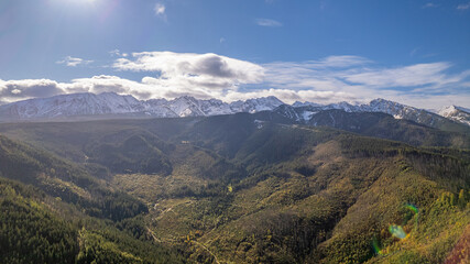 Naklejka premium Sunlit Tatra Mountains Above Forested Valley, Early Snow on Peaks, Zakopane Region, Poland – Aerial Drone View