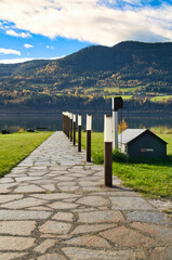 Stone path to the lake shore in front of a mountain backdrop on an autumn day.