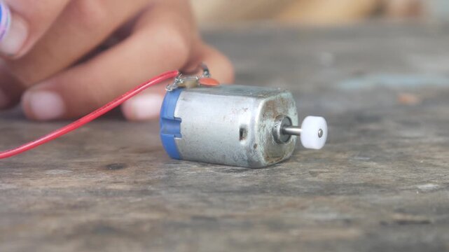 The rotating DC motor dynamo is placed on a wooden surface.
