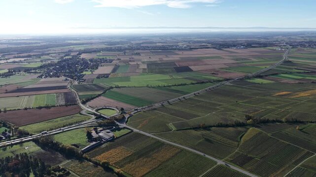 Aerial view of the patchwork fields and roads contrasting with the built environment, creating a mosaic of textures and tones, Rouffach, Grand Est, France.