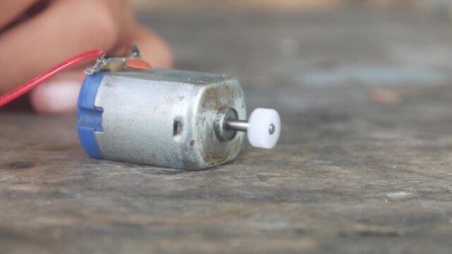 The rotating DC motor dynamo is placed on a wooden surface.